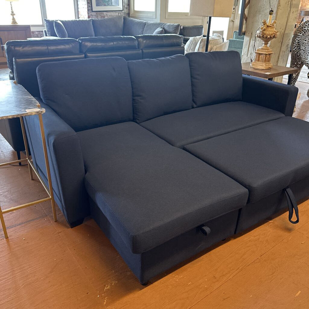 Blue sectional sofa in a showroom setting with other furniture in the background.