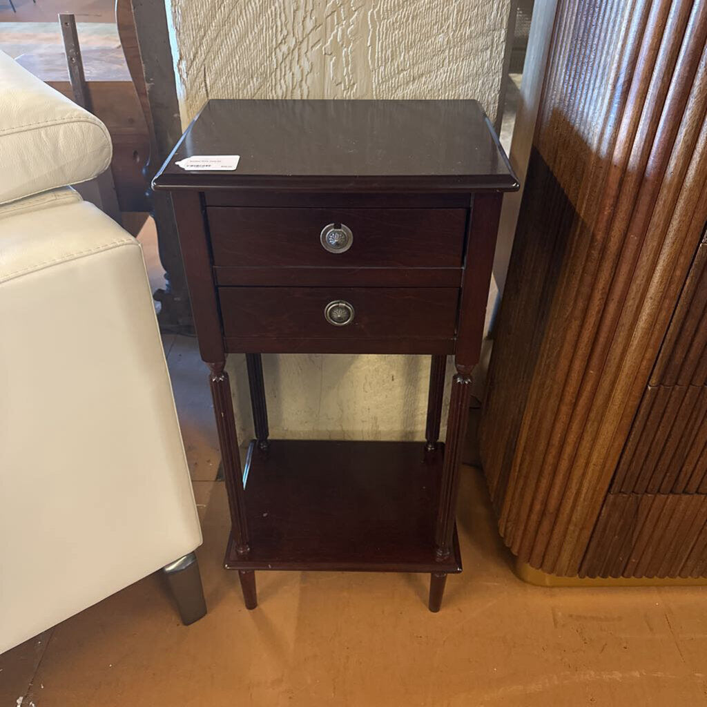 Wooden side table with two drawers and a shelf in a room setting.