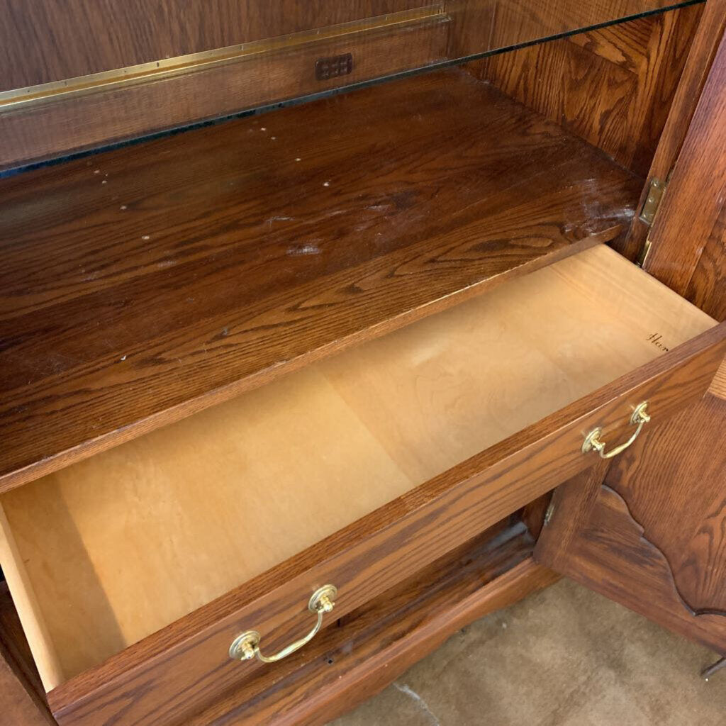 Wooden display cabinet with glass top and open drawer, showing signs of wear.