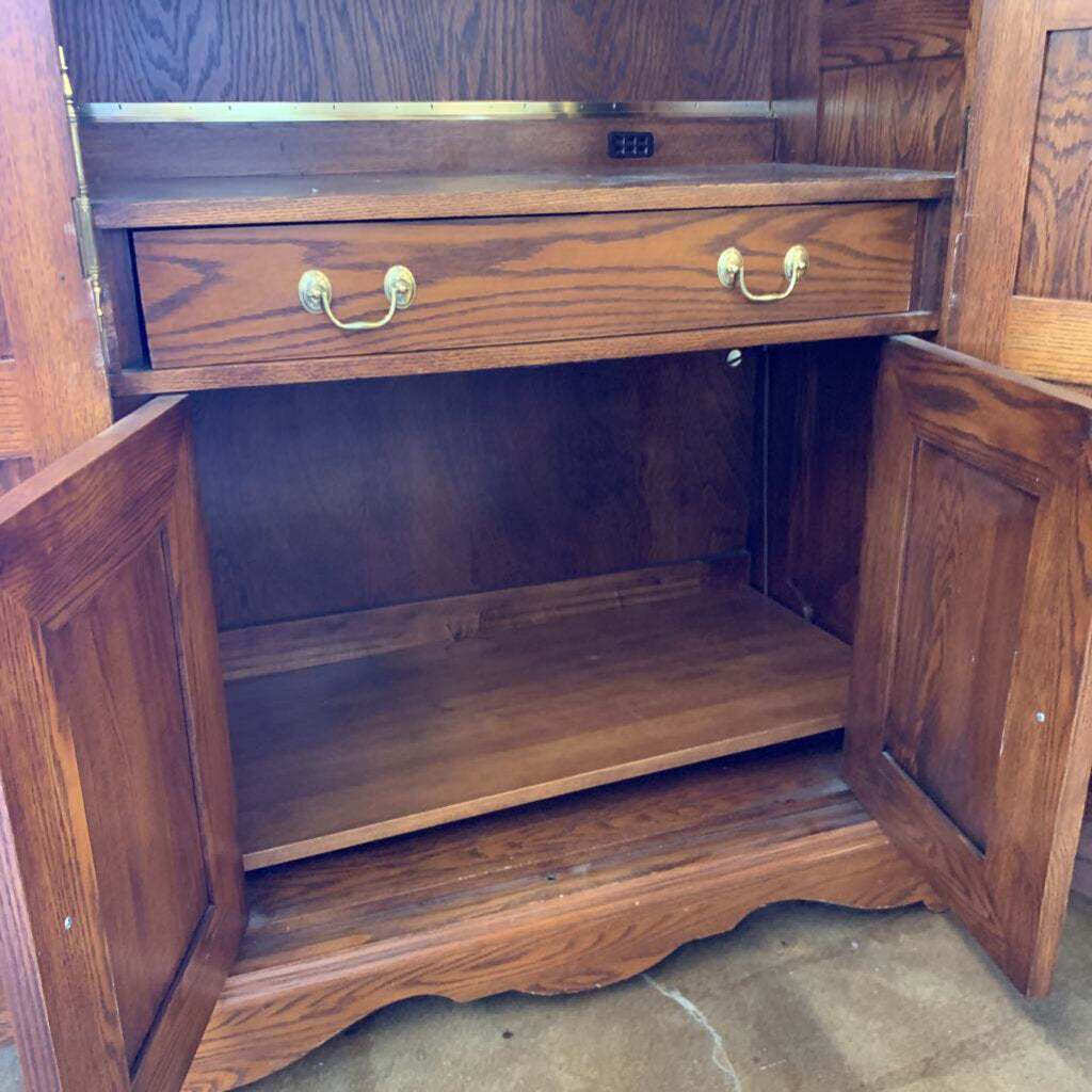 Wooden cabinet with open doors and a drawer, showing wear and tear.