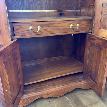 Wooden cabinet with open doors and a drawer, showing wear and tear.