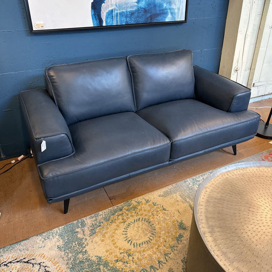 Blue leather sofa in a room with a rug and table