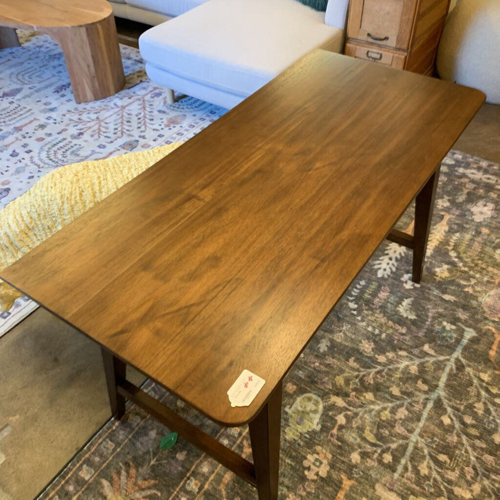 Wooden table in a living room setting with a rug and furniture in the background