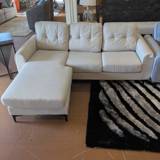 White sectional sofa in a living room setting with a rug and other furniture.