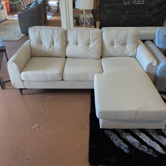 Beige sectional sofa in a room with a rug and furniture.