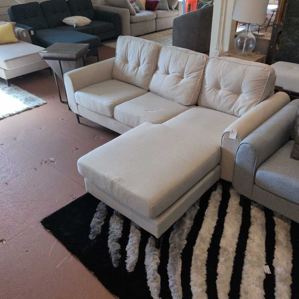 Beige sectional sofa in a living room setting with other furniture.