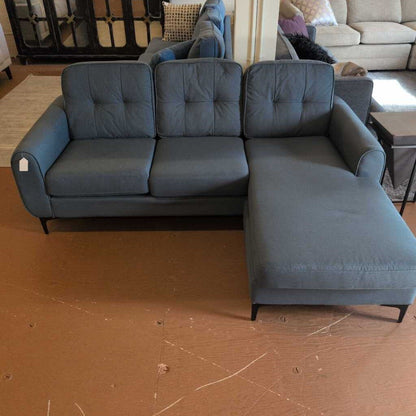 Gray sectional sofa on a brown floor with a blurred background