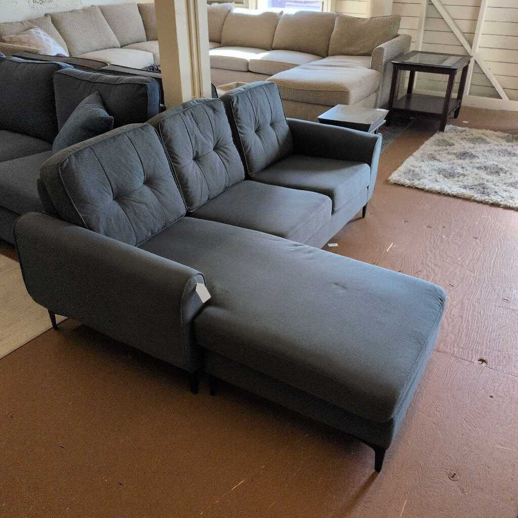 Gray sectional sofa in a room with beige walls and carpet.