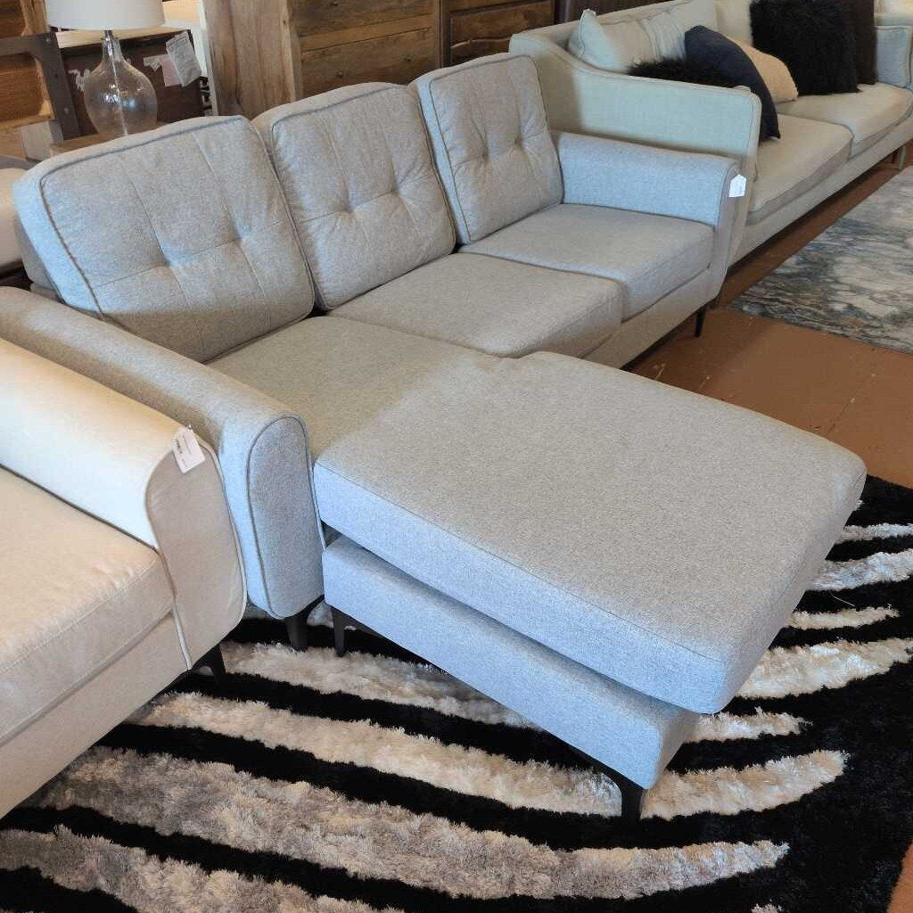 Beige sectional sofa with ottoman on a striped rug