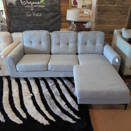 Gray sectional sofa in a room with a black and white patterned rug.