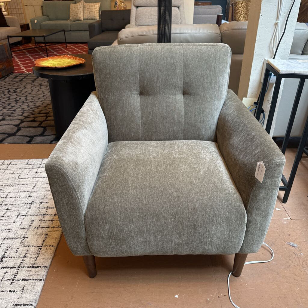Gray armchair in a showroom setting with other furniture in the background