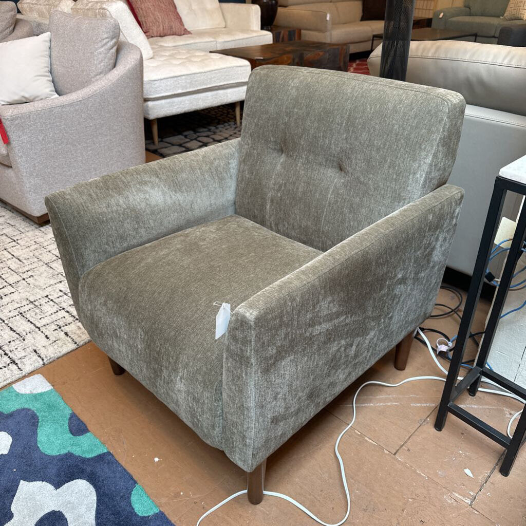 Gray armchair in a showroom setting with other furniture around