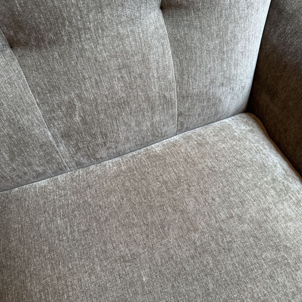 Close-up of a gray upholstered chair with tufted backrest