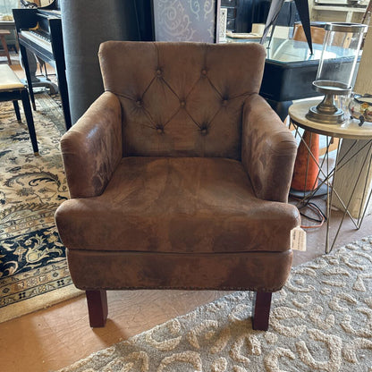 Brown armchair in a room with a patterned rug and furniture.