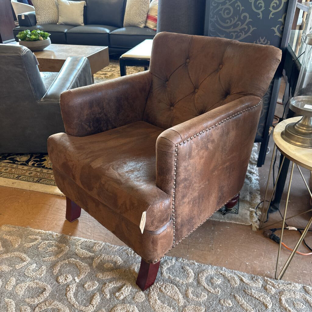 Brown leather armchair in a living room setting with a coffee table and sofa.