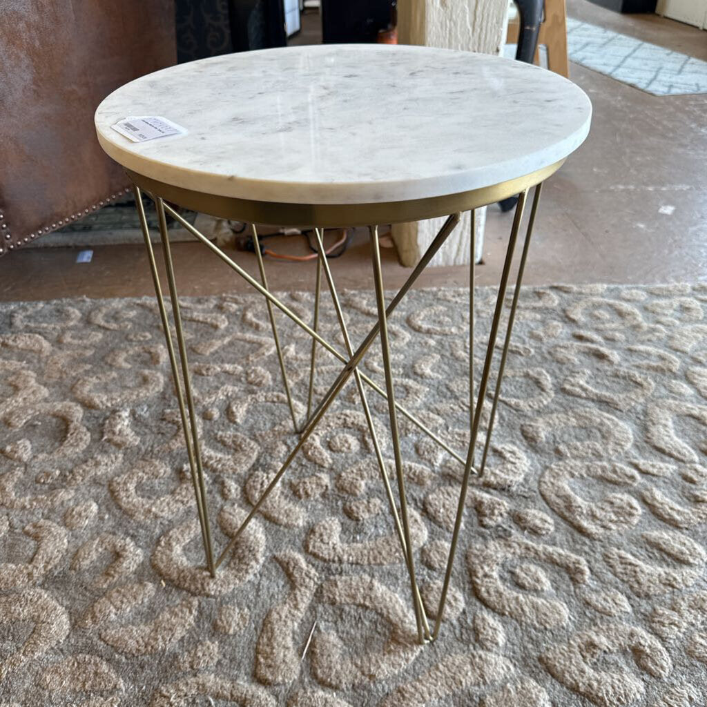 Small round table with marble top and gold metal legs on a textured carpet