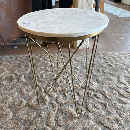 Small round table with marble top and gold metal legs on a textured carpet