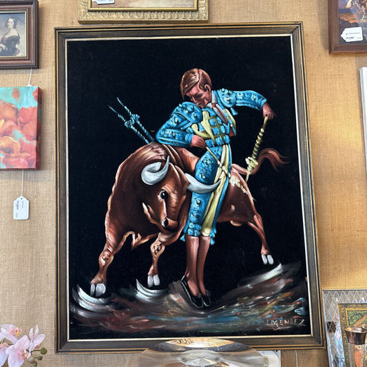 Painting of a bull rider on a dark background, framed and displayed on a wall.