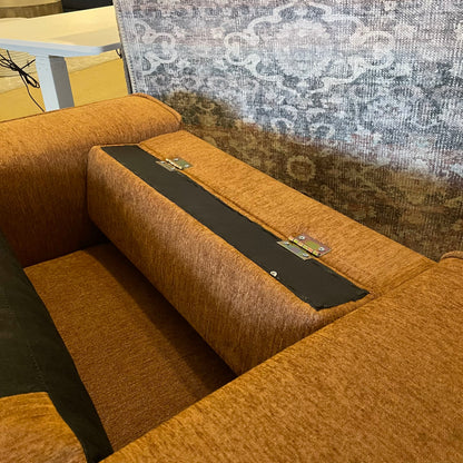 Brown sectional sofa with a black tray on a textured wall background