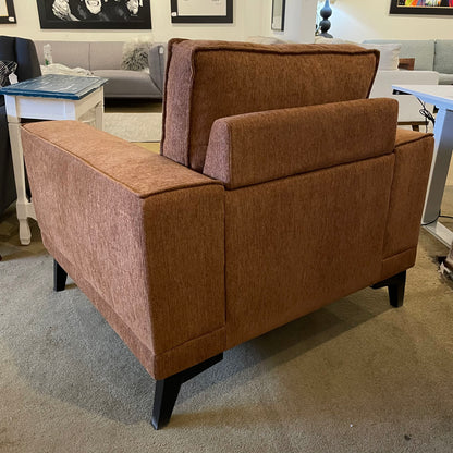 Brown upholstered chair in a room with furniture and decor.