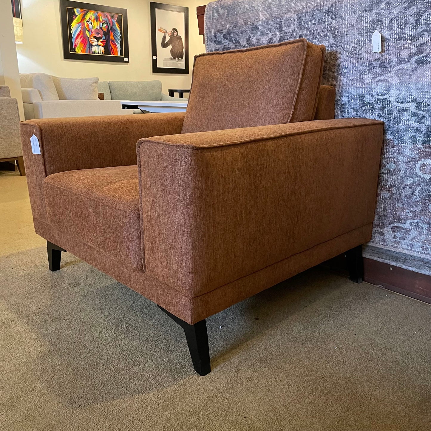 Brown armchair in a showroom setting with other furniture and decor in the background.