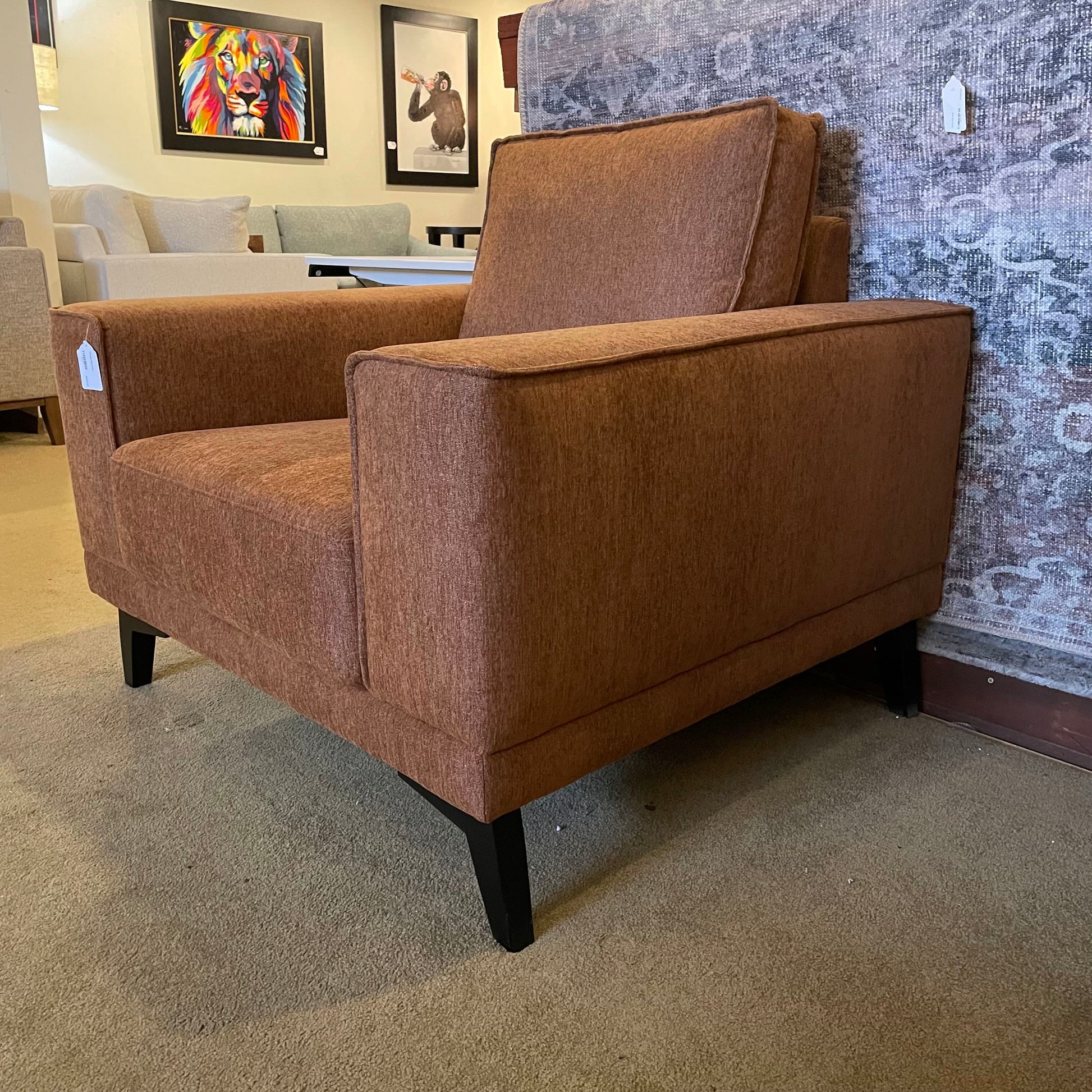 Brown armchair in a showroom setting with other furniture and decor in the background.