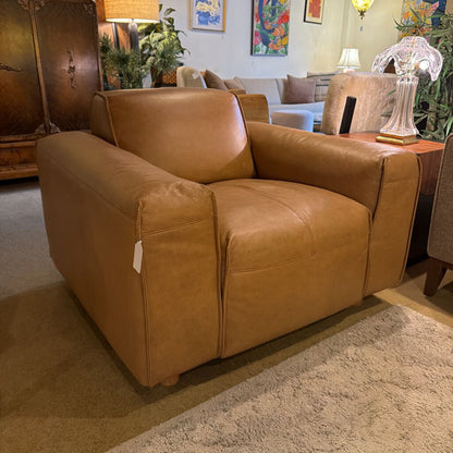 Brown leather armchair in a living room setting with decor elements.