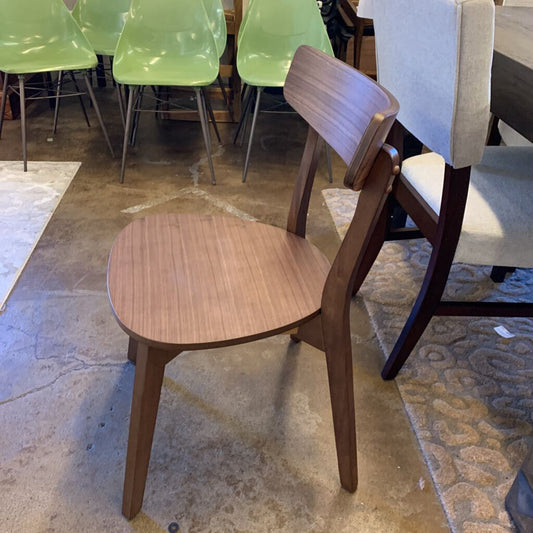 Wooden chair with a cushioned seat in a room with other chairs and furniture.