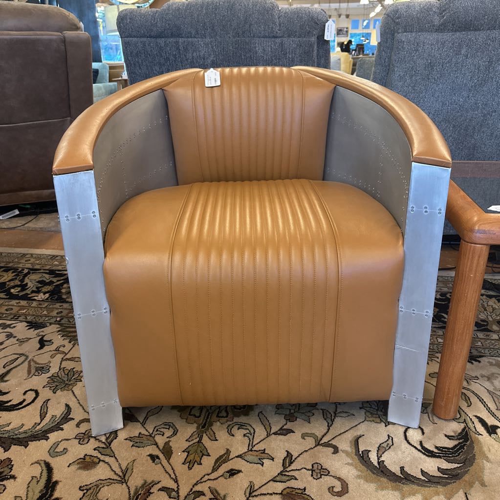 Brown leather chair with metal armrests on a patterned carpet