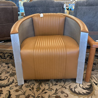 Brown leather chair with metal armrests on a patterned carpet