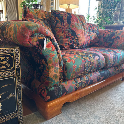 Multicolored floral-patterned sofa with wooden legs in a room setting.