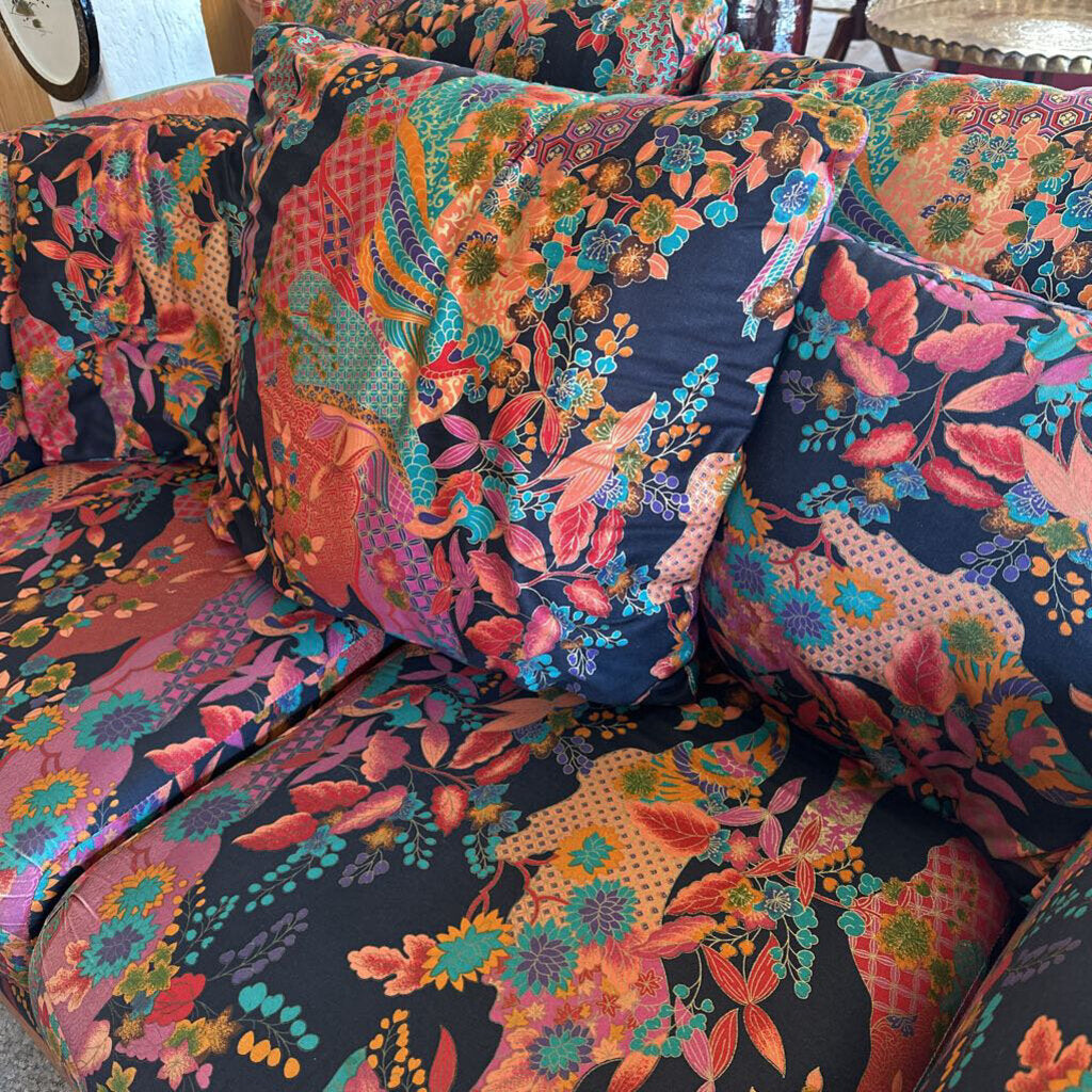 Colorful floral-patterned sofa with vibrant colors on a wooden floor.