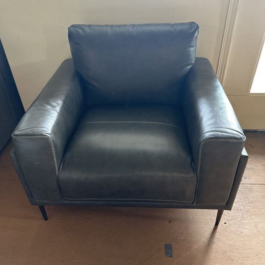 Blue leather armchair on a wooden floor with a neutral wall background
