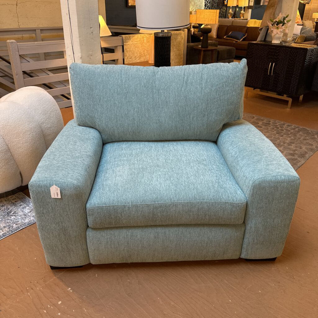 Light blue armchair in a showroom setting with other furniture.