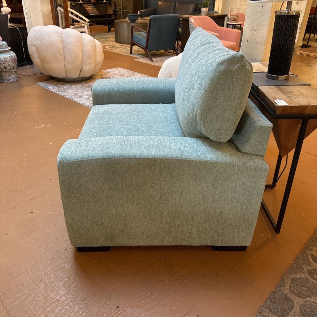 Light blue armchair in a showroom setting with other furniture in the background.