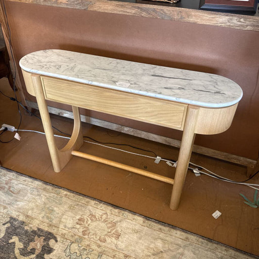 Wooden console table with marble-like top on a brown floor.