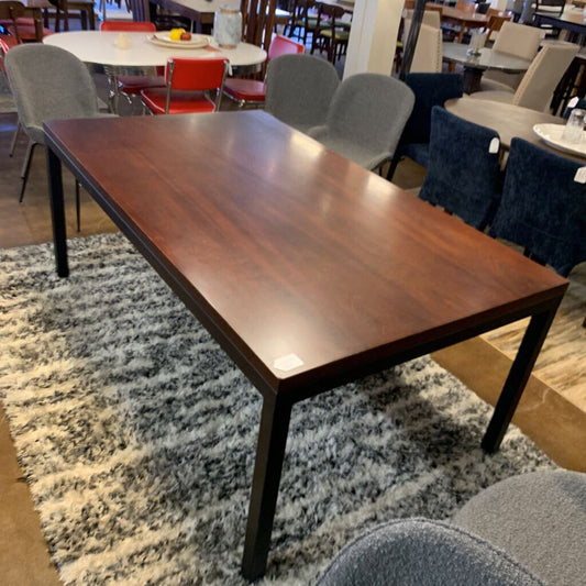 Wooden dining table in a room with chairs and tables in the background