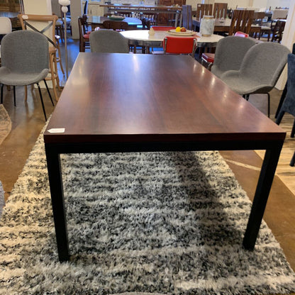 Wooden dining table in a room with chairs and tables in the background