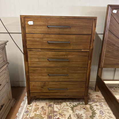 Wooden dresser with four drawers on a patterned rug.