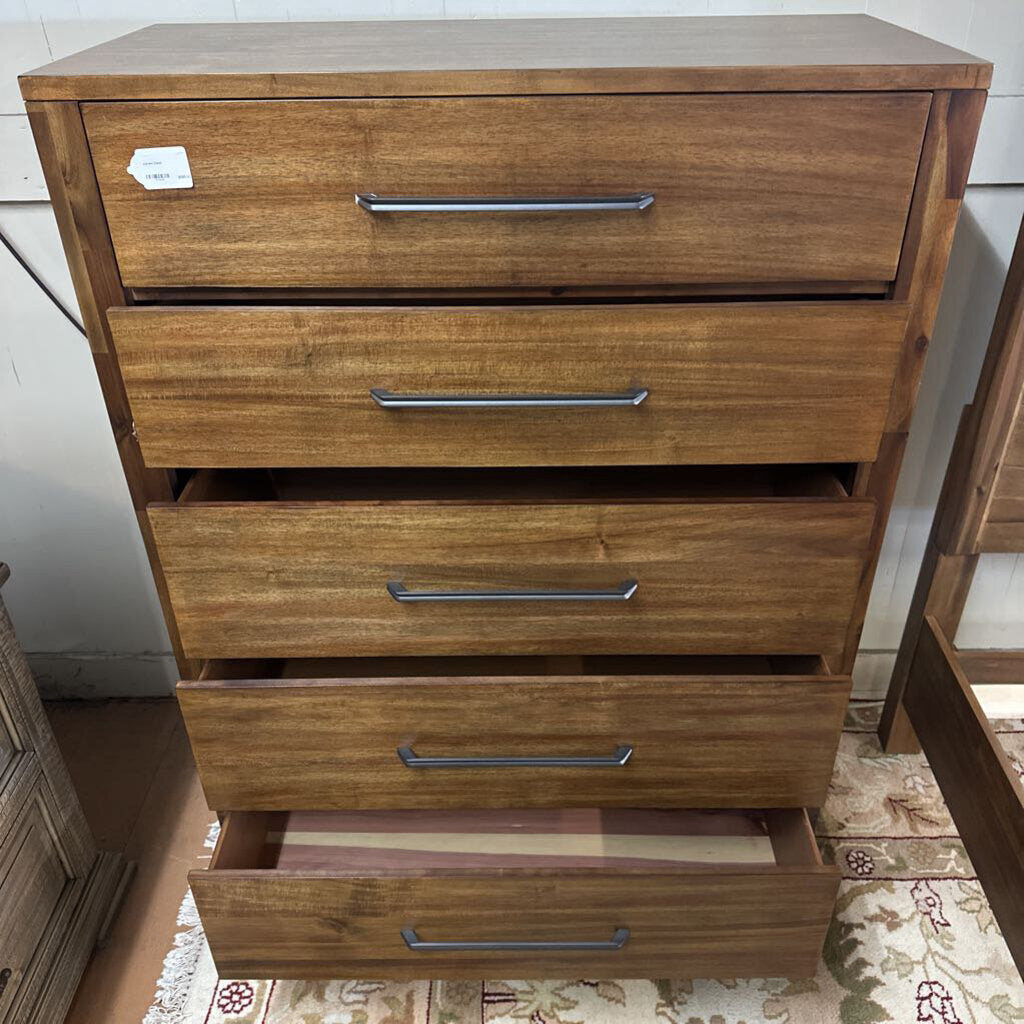 Wooden dresser with four drawers, one open, on a patterned rug.