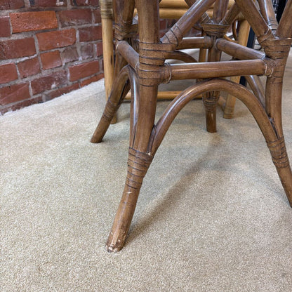 Close-up of a wooden chair leg on a carpeted floor with a brick wall in the background.