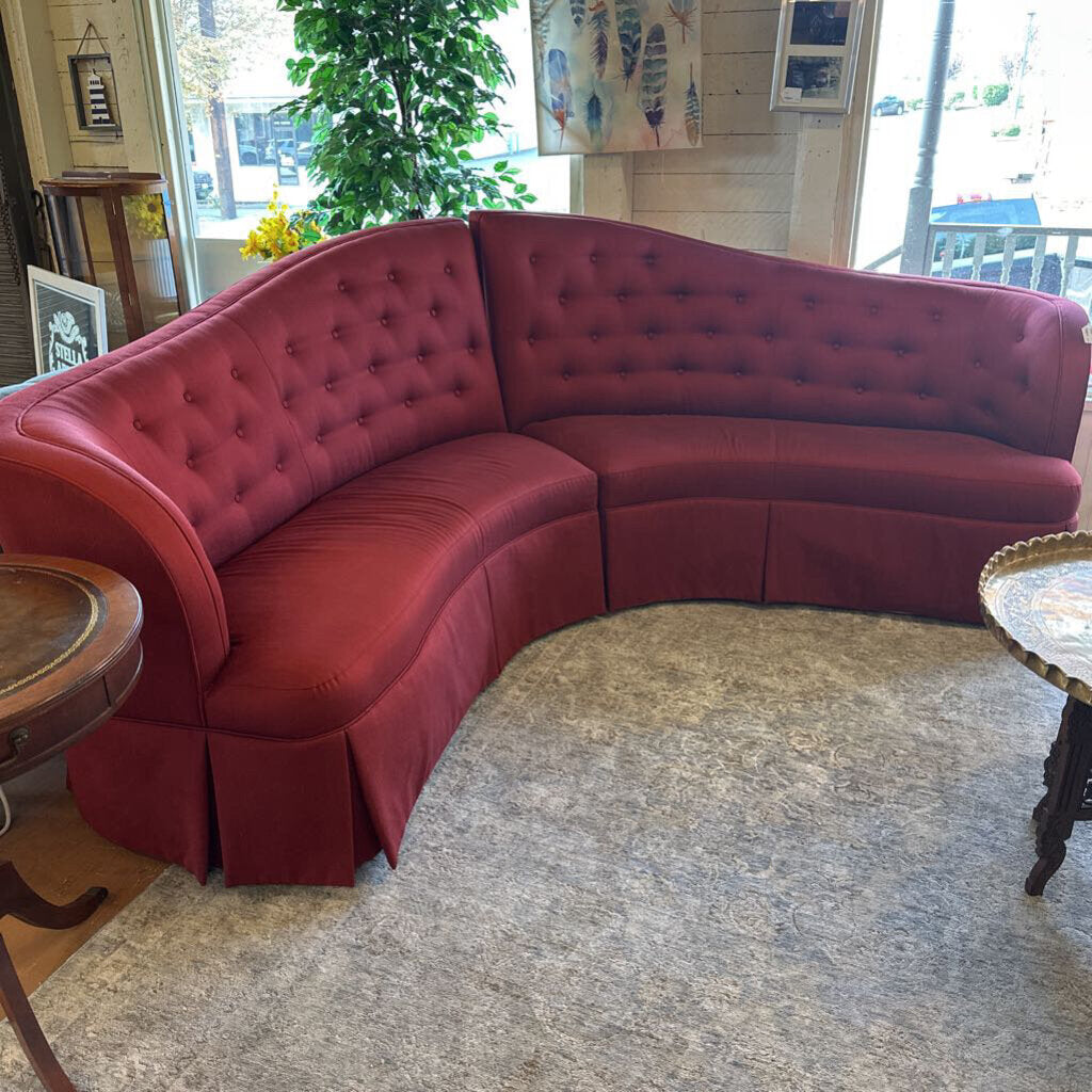 Red tufted sectional sofa in a room with decor elements.