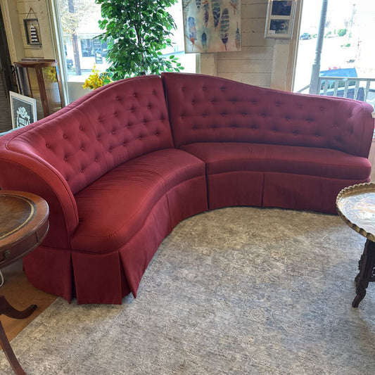 Red tufted sectional sofa in a room with decor elements.