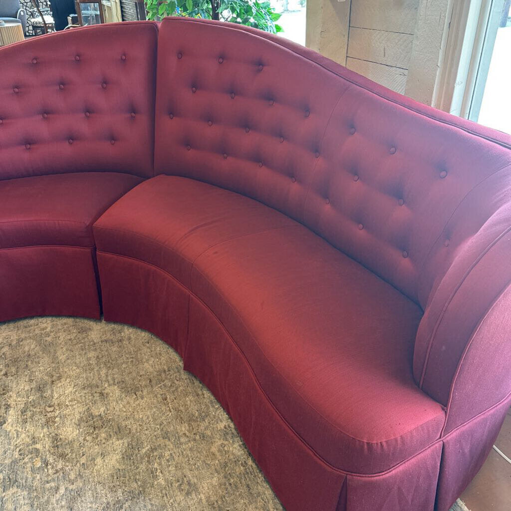 Red tufted curved sofa in a room with a marble floor.