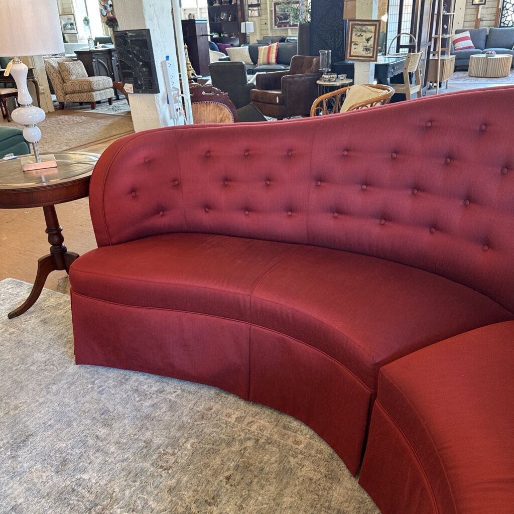 Red curved sofa in a showroom with other furniture in the background