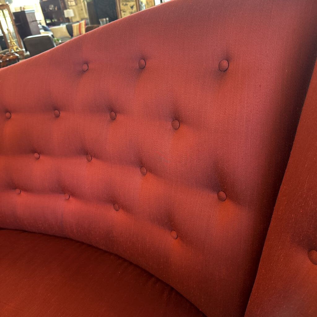 Close-up of a red tufted headboard with button details.