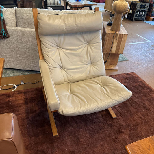 Beige cushioned chair with wooden frame in a room setting