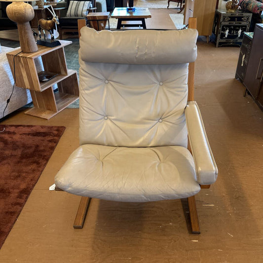 White cushioned chair in a room with furniture and decor.