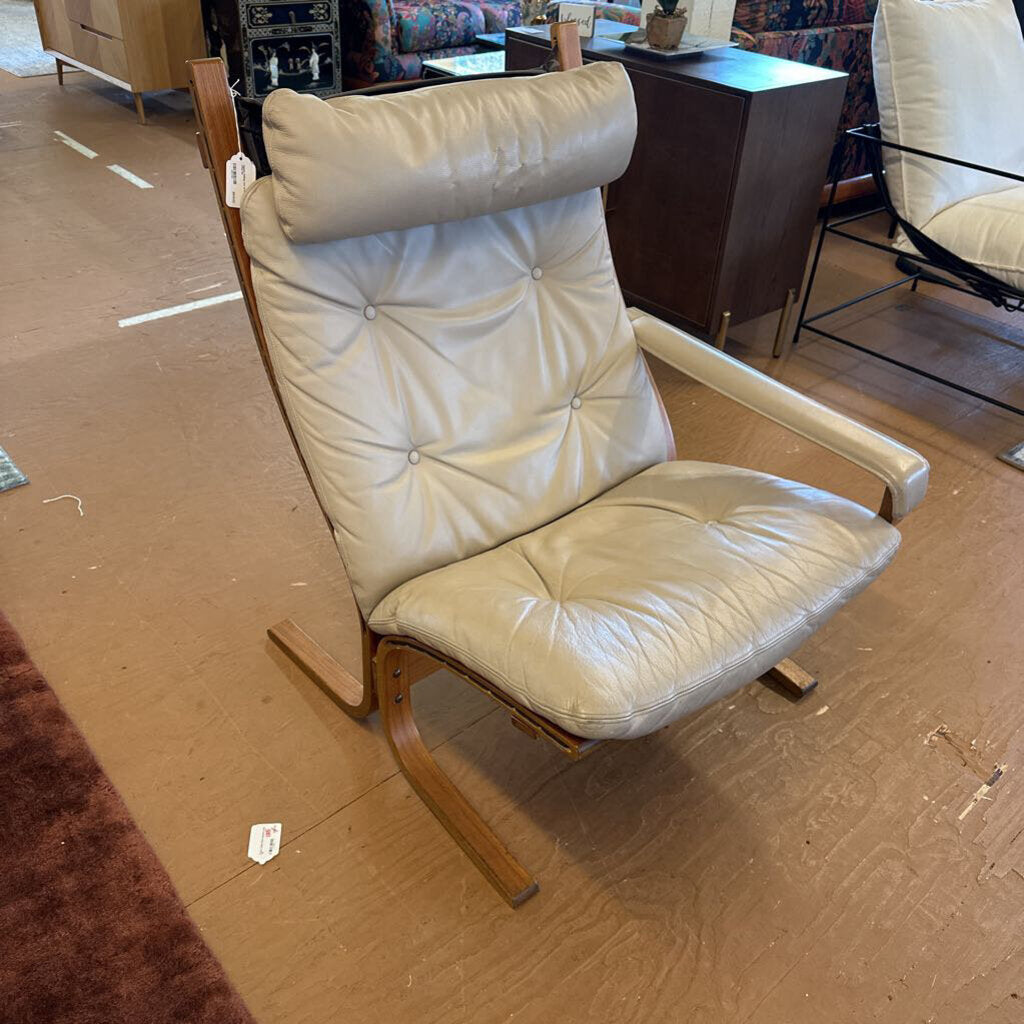 Beige leather armchair with wooden frame on a brown floor
