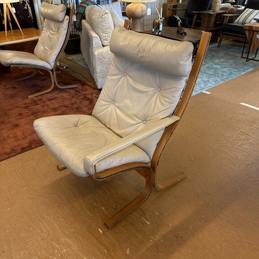 White cushioned chair with wooden frame on a showroom floor